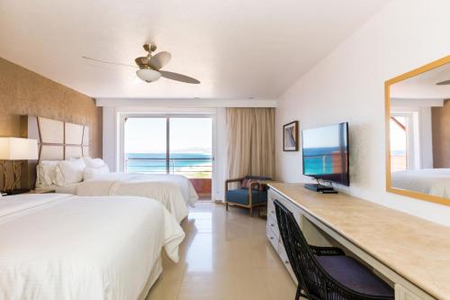 a hotel room with two beds and a flat screen tv at The Westin Los Cabos Resort Villas - Baja Point in El Bedito