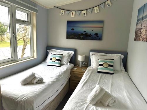 two twin beds in a room with two windows at Driftwood Lodge in Salcombe