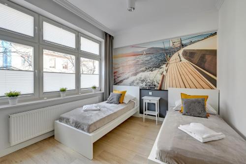 a bedroom with two beds and a painting on the wall at Grand Apartments - Apartamenty Haffnera w samym sercu Sopotu in Sopot
