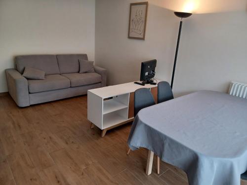 - un salon avec un canapé et une table avec un ordinateur dans l'établissement T2 grande terrasse Wi-Fi parking gratuit, à Voiron