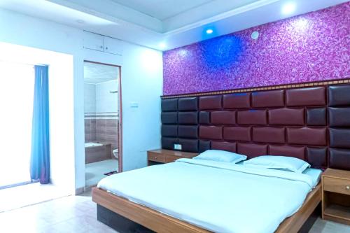 1 dormitorio con cama grande y pared morada en Impulse Ocean View, en Cox's Bazar