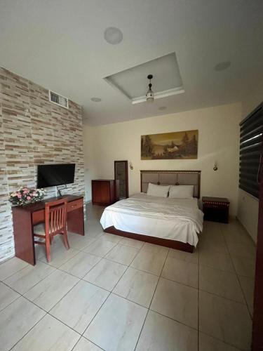 a bedroom with a bed and a desk with a television at Nojoom Hotel in Amman