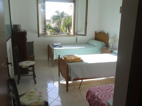 a room with two beds and a table and a window at Rocca tagliata Marsala in Marsala
