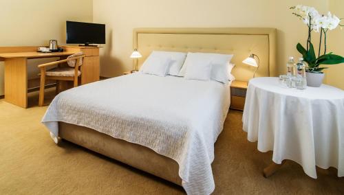 a bedroom with a white bed and a desk and a computer at Hotel Komeda in Ostrów Wielkopolski