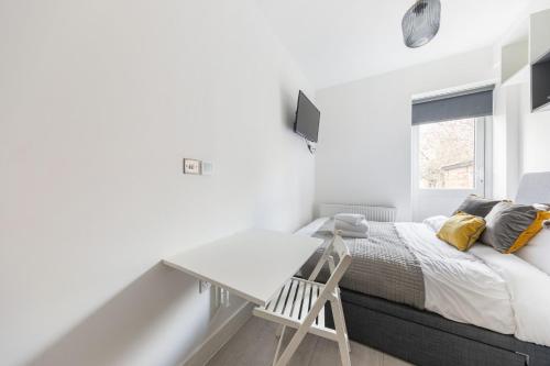 a white bedroom with a bed and a desk at Functional Double With An Ensuite Toilet And Shower Near Tube And Bus Stations in London