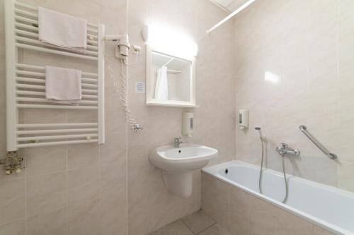 W łazience znajduje się umywalka, toaleta i wanna. w obiekcie Gartner Hotel w Budapeszcie