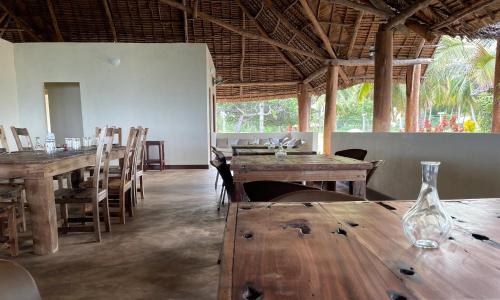 a dining room with wooden tables and chairs at Kileleni in Kilindoni