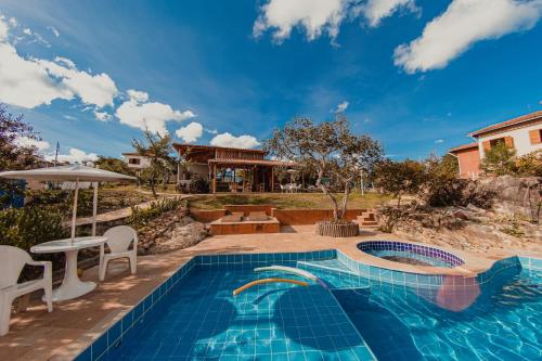 una piscina con tavolo e sedie accanto a una casa di Vila Espinhaço a Diamantina