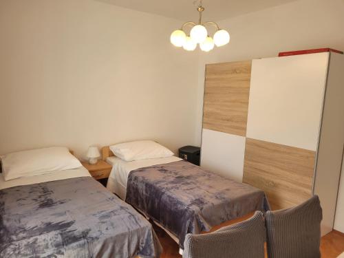 um pequeno quarto com 2 camas e um lustre em Roko em Trogir