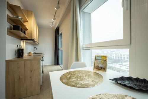 a kitchen with a white table and a large window at WiguryTower Apartaments 63' in Łódź