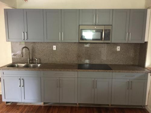 a kitchen with white cabinets and a sink and a microwave at 1BR Historic Art Deco Charm Meets Modern Comfort- Huge Tropical Garden in Posh Coral Gables-10 min Airport in Miami