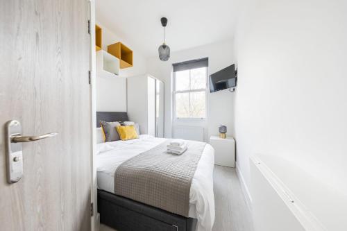 a white bedroom with a bed and a window at Cozy Ensuite Bedroom for Two near Tufnell Park in London