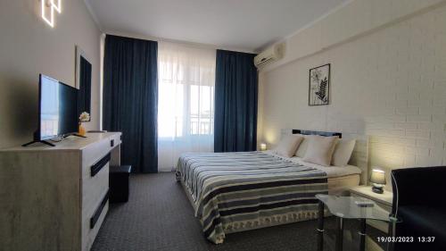 a hotel room with a bed and a television at Guest house Marina in Obzor