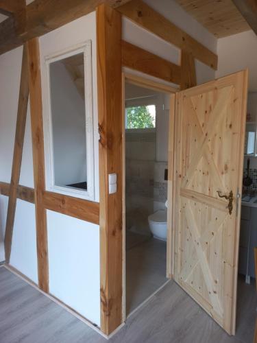 a bathroom with a wooden door and a toilet at Zagroda Nadmorska Brzezina in Jastrzębia Góra