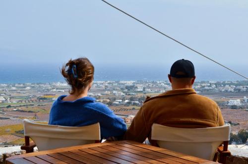 a man and woman sitting at a table looking out over a city at Bluegonia in Éxo Goniá