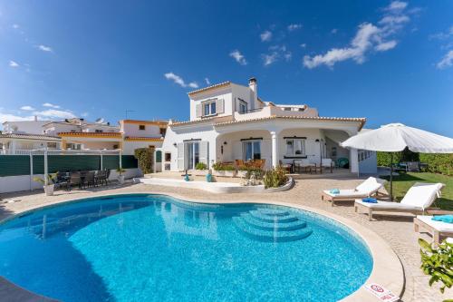 a villa with a swimming pool in front of a house at Lagos - Pool & Garden in Lagos