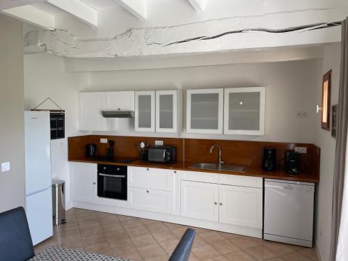une cuisine avec des armoires blanches et un évier dans l'établissement Gîte à 10mns du Treport et Criel sur Mer, à Saint-Martin-le-Gaillard