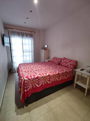 1 dormitorio con 1 cama con colcha roja y ventana en Acogedor apartamento cerca de la playa, en Moncófar
