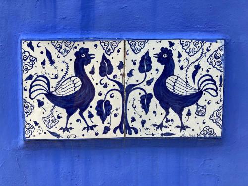 a tile with three roosters on a blue wall at Casa Gallinera in Benissiva