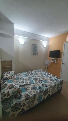 a bedroom with a bed with a floral comforter at 2 minutes from Roseau, Cozy studio with shared pool in Roseau