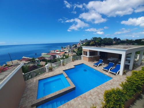 a house with a swimming pool and a view of the ocean at 2 minutes from Roseau, Cozy studio with shared pool in Roseau