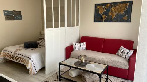 a living room with a red couch and a bed at Charmant Studio 25 m2, 900m de la plage in Les Sables-dʼOlonne