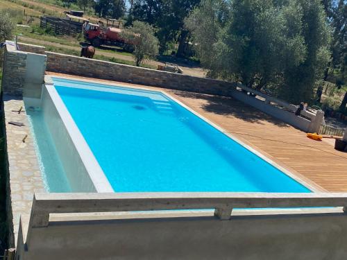 a blue swimming pool with a wooden deck at Charmante Propriété Arborée in Borgo