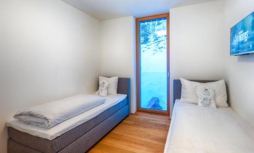 two beds in a room with a window at Residence Bellevue - incl Summercard in Zell am See