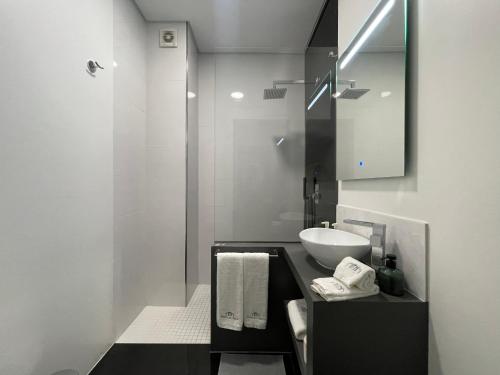 a white bathroom with a sink and a mirror at PORTA NOVA Historic Center - Apartments Collection by Perpetual Relax in Braga