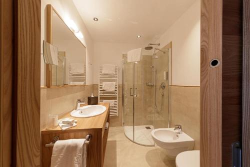 een badkamer met een douche, een wastafel en een toilet bij Family Hotel Posta in Santa Cristina in Val Gardena