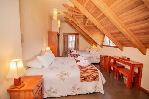 2 łóżka w pokoju z drewnianym sufitem w obiekcie Vientos del Sur w mieście Pucón