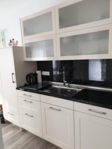 a kitchen with white cabinets and a sink at Maje Am alten Binnenhafen in Emden