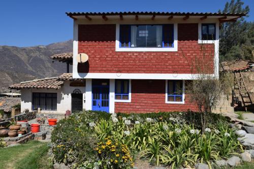 a red brick house with a blue door and some flowers at La Casita de mi Abuela in Mancos