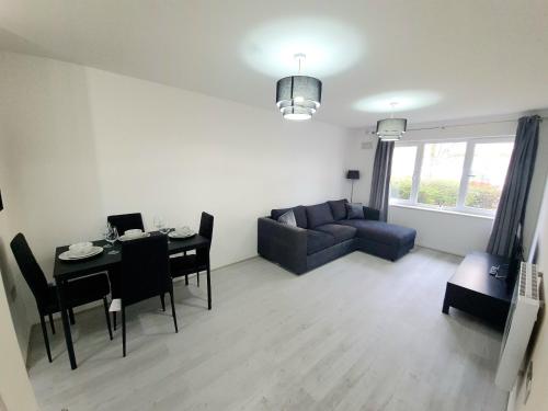 a living room with a couch and a table and chairs at 2 bedroom light, spacious aptmnt nr Heathrow in Cranford