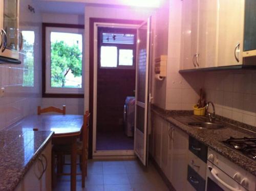 una cocina con una puerta que da a una cocina con mesa en Vacacions nas Neves - Holidays, en Nieves