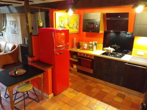 Il comprend une cuisine équipée d'un réfrigérateur rouge et d'une table. dans l'établissement Longère lotoise 5 chambres, à Sénaillac-Latronquière