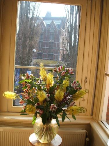 a vase of flowers on a table in front of a window at Hotel Museumzicht in Amsterdam