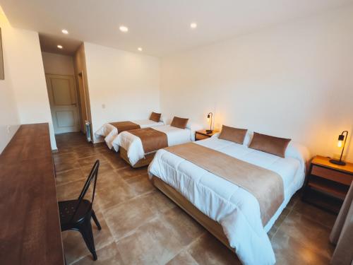 a hotel room with two beds and a chair at Destino Calafate in El Calafate