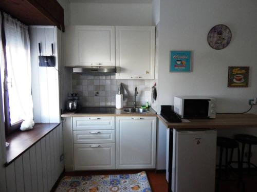 a small kitchen with white cabinets and a microwave at Pian del Falco in Sestola