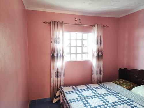 a bedroom with a bed and a window at Camp-Flo 3br Guest House-Eldoret in Eldoret
