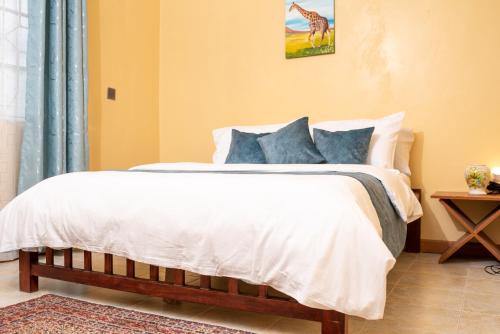 Un dormitorio con una cama blanca con una foto de jirafa en la pared en Augustine Cosy Homes en Nakuru