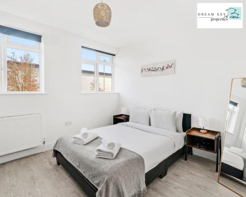 Un dormitorio blanco con una cama con toallas. en Spacious Two Bedroom Apartment by Dream Key Properties Short Lets & Long Lets Uxbridge- 1, en Uxbridge