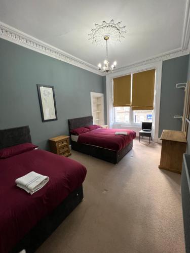 a bedroom with two beds and a chandelier at Sauchiehall Street West End Apartment in Glasgow