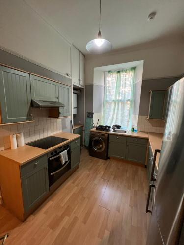 a large kitchen with green cabinets and a wooden floor at Sauchiehall Street West End Apartment in Glasgow