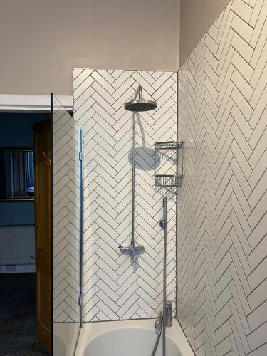 a bathroom with a shower with a white tile wall at Sauchiehall Street West End Apartment in Glasgow