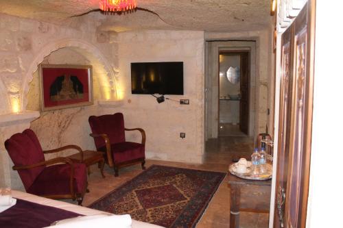 a living room with chairs and a tv on a wall at Solo Cave Suites in Nevsehir