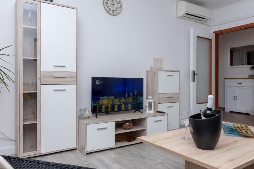 a kitchen with white cabinets and a table with a tv at Blue Mile Apartman Split in Split