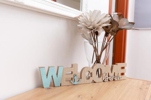 a wooden sign on a table with a vase of flowers at Blue Mile Apartman Split in Split