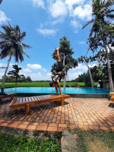 a man sitting on a bench in front of a pool at Rice Rice Villas in Tissamaharama