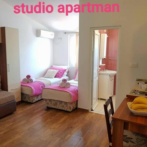 two beds in a room with a table and a kitchen at Apartment Dasic in Bar